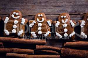 Gingerbread cookies and cinnamon sticks arranged on wooden plank