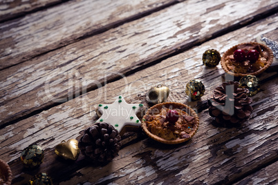 Cookies and christmas decoration arranged on wooden plank