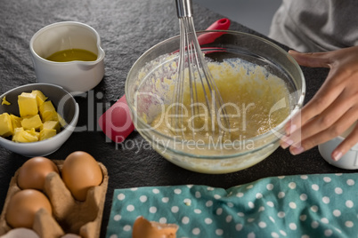 Woman whisking batter of beaten eggs and milk in a bowl