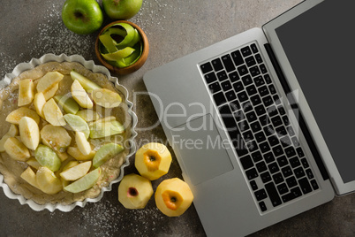 Laptop with apple tart and peeled green apple