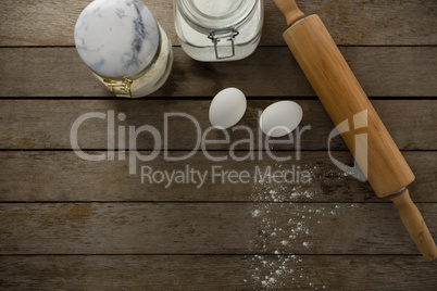 Rolling pin, eggs and glass containers on a wooden table