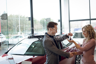 Salesman doing handshake while giving keys to customer
