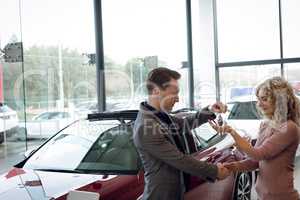 Salesman doing handshake while giving keys to customer