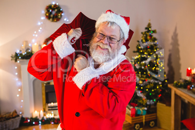 Portrait of santa claus holding gift sack at home