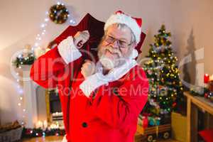 Portrait of santa claus holding gift sack at home