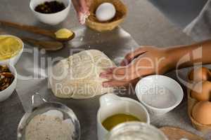 Woman preparing dough surrounded with various ingredients