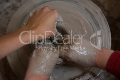 Female potter assisting boy in molding a clay