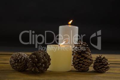Close up of pine cones with illuminated candles on table