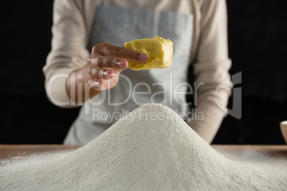 Woman adding butter cube into flour