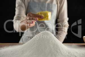 Woman adding butter cube into flour