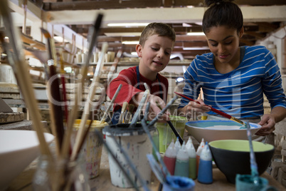 Female potter and boy painting bowl