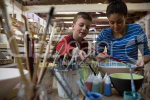 Female potter and boy painting bowl