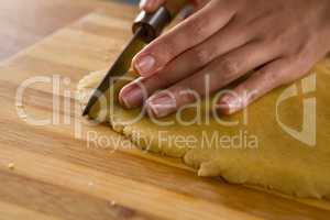 Woman slicing dough on chopping board