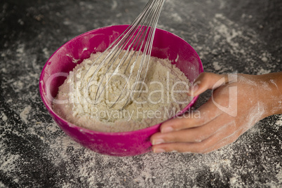 Woman whisking flour in bowl