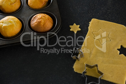 Plain cupcakes in baking tray with star shape dough and cutter
