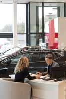 Female customer discussing with salesman in carshowroom
