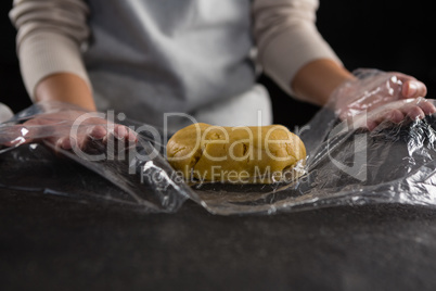 Woman wrapping dough in a plastic wrap