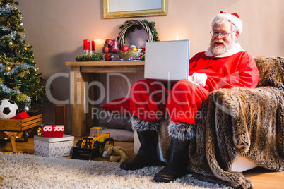 Santa claus sitting and using laptop at home