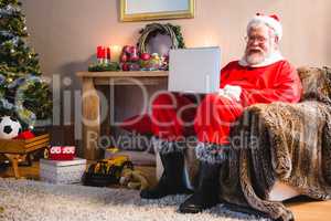 Santa claus sitting and using laptop at home