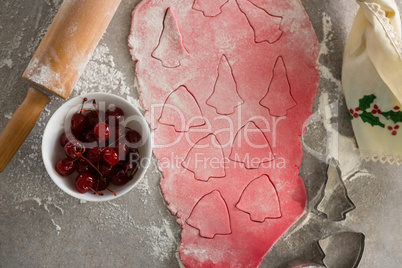 Red cherries in bowl with cookies dough and cutter