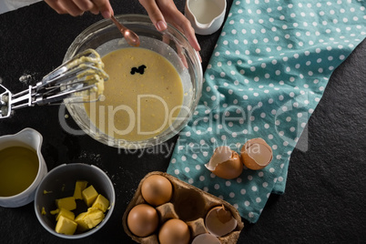 Woman adding food color to a bowl of batter