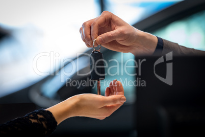 Cropped image of salesman giving car key to customer