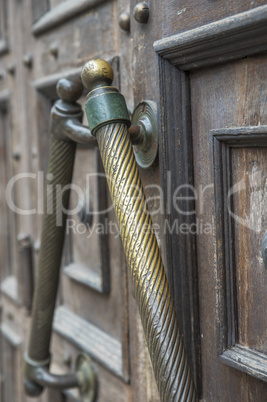 copper door handle on a brown wooden door