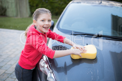 Teenage girl washing a car on a sunny day
