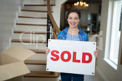Woman standing in the living room holding sold sign