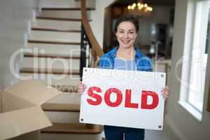Woman standing in the living room holding sold sign