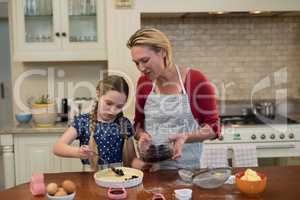 Mother and daughter preparing blue berry pie