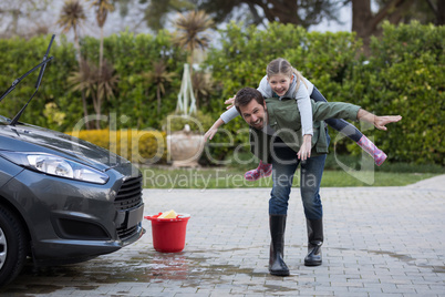 Teenage girl and father washing a car