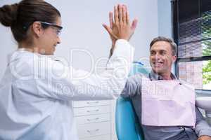 Happy dentist giving high five to man