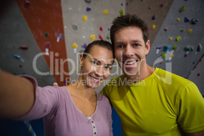 Portrait of smiling athletes standing by climbing wall in fitness club