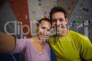Portrait of smiling athletes standing by climbing wall in fitness club