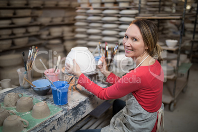 Portrait of female potter holding color tube