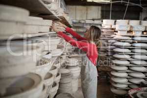 Female potter placing craft product in shelf