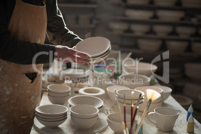 Mid section of male potter holding bowls