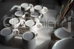 Close-up of ceramic mugs arranged on worktop