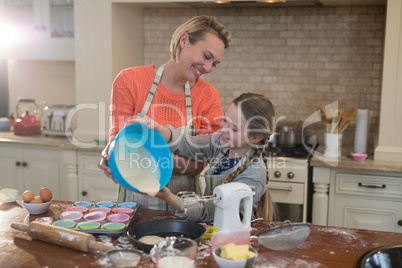 Mother and daughter preparing cup cake in kitchen