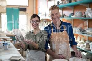 Portrait of male and female potter checking plate