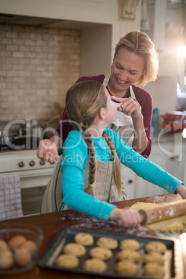 Happy mother and daughter having fun while preparing cookies in kitchen