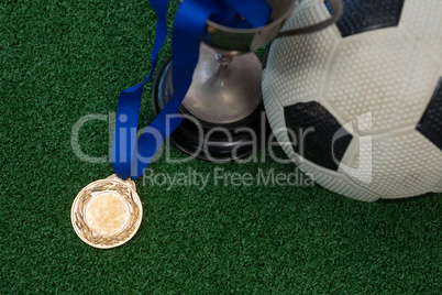 Football, trophy and medal on artificial grass