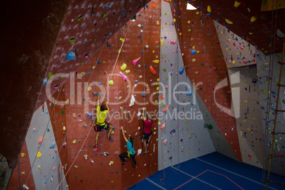 View of trainer and athletes rock climbing in gym