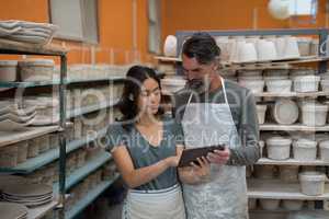 Male and female potter using digital tablet