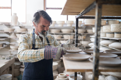 Male potter placing plate on shelf