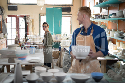 Male and female potter interacting while working