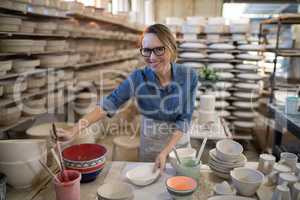 Female potter painting bowl