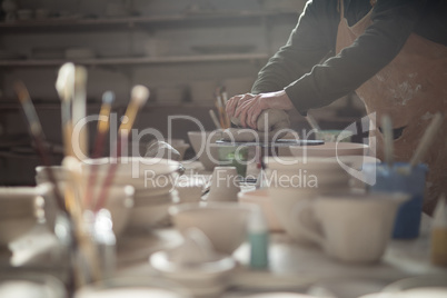 Mid section of male potter molding a clay