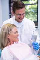 Dentist showing mirror to smiling patient